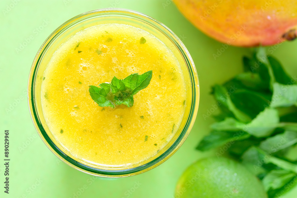 Cooling Mango mint smoothie, summer drink on green table, Yellow Tropical Smoothie made with mango, mint and lime juice. Cooling Mango mint smoothie, summer drink on green table, Yellow Tropical Smoothie made with mango, mint and lime juice.