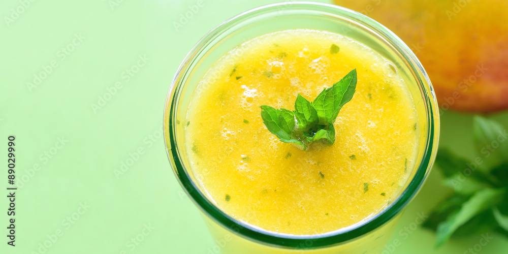 Cooling Mango mint smoothie, summer drink on green table, Yellow Tropical Smoothie made with mango, mint and lime juice. Copy space. Cooling Mango mint smoothie, summer drink on green table, Yellow Tropical Smoothie made with mango, mint and lime juice. Copy space.