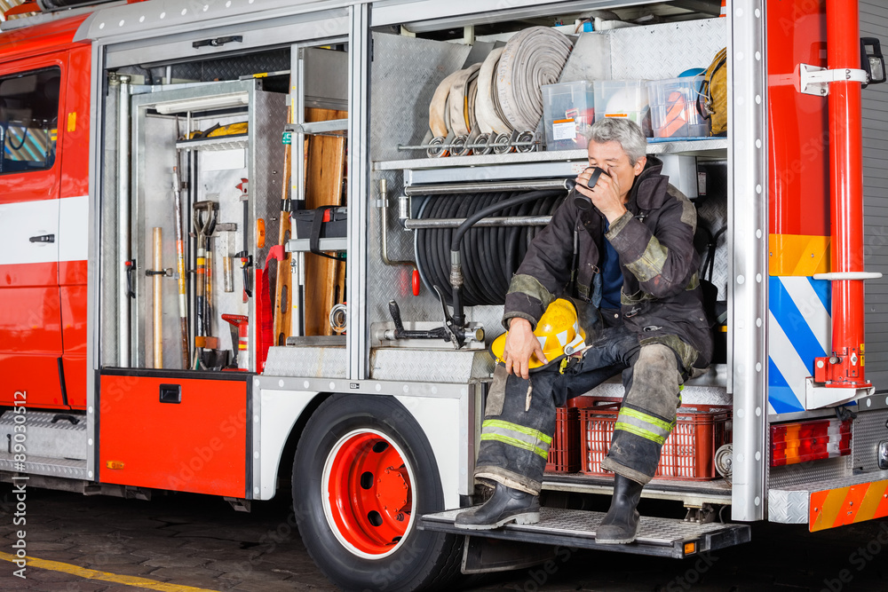 Fototapeta premium Fireman Drinking Coffee While Sitting In Truck