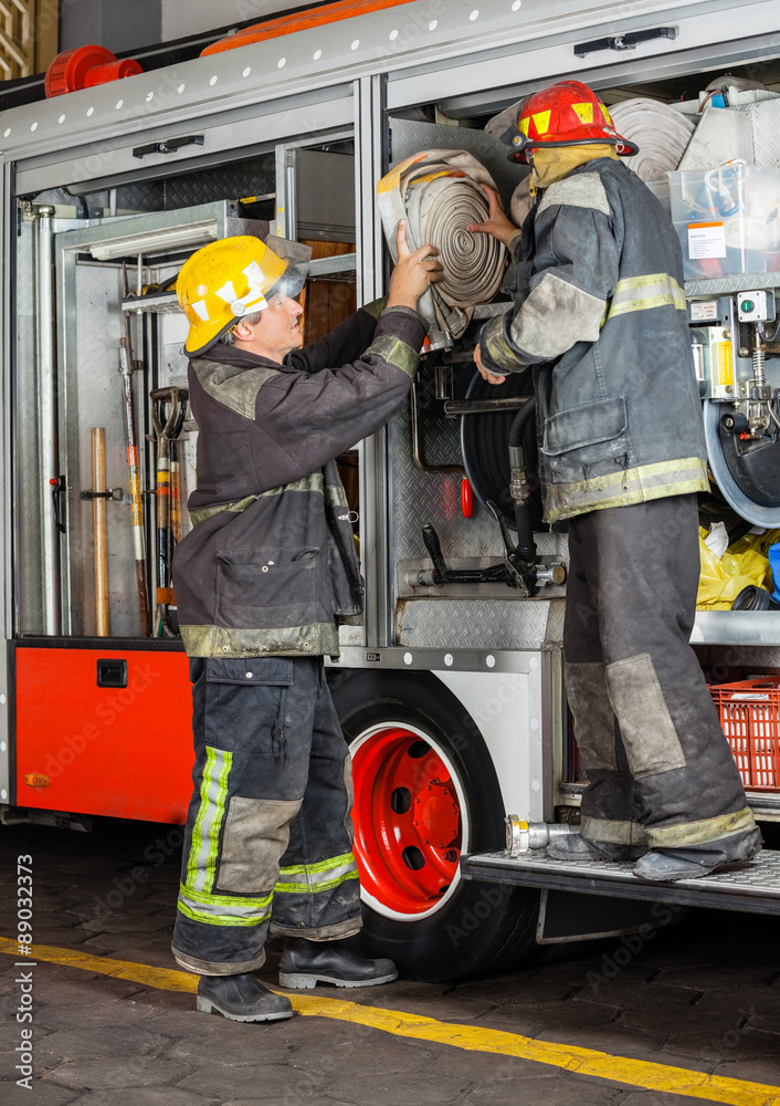 Obraz premium Firefighters Removing Hose From Truck
