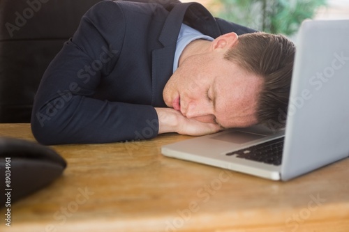 Exhausted businessman sleeping on his laptop