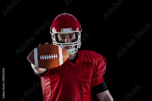 Portrait of american football player showing football to camera