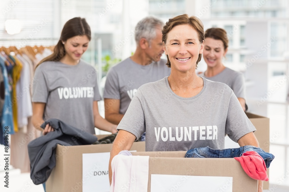 Smiling female volunteer carrying donation box