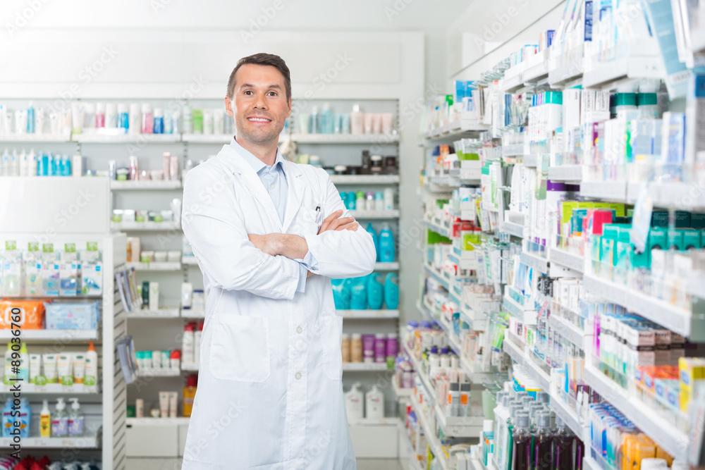 Smiling Pharmacist Standing Arms Crossed In Pharmacy