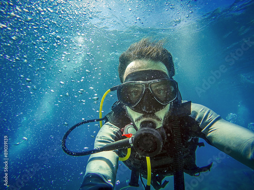 Diving. Self portrait of young diver in the sea. Blue water background.