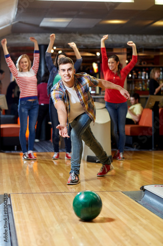 happy young man throwing ball in bowling club