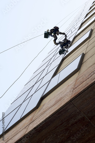vertical climber worker hanging on ropes to cleaning  windows in modern building
