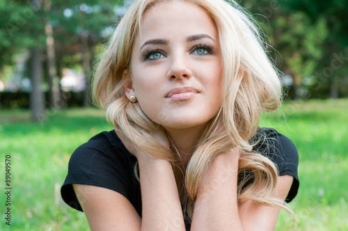 Young blond woman looking up sitting in the park