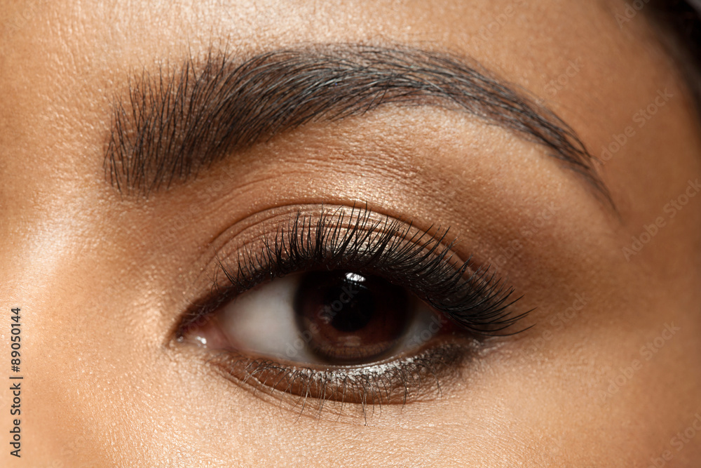Fototapeta premium Zbliżenie: makijaż oczu z długimi rzęsami i brązowymi brwiami czarnej kobiety