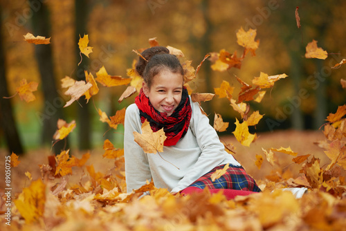 girl sitting on yellow leaves in the park