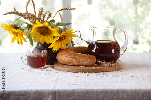 kvass (kvas) in a transparent jug, bread and a bouquet of sunflo photo