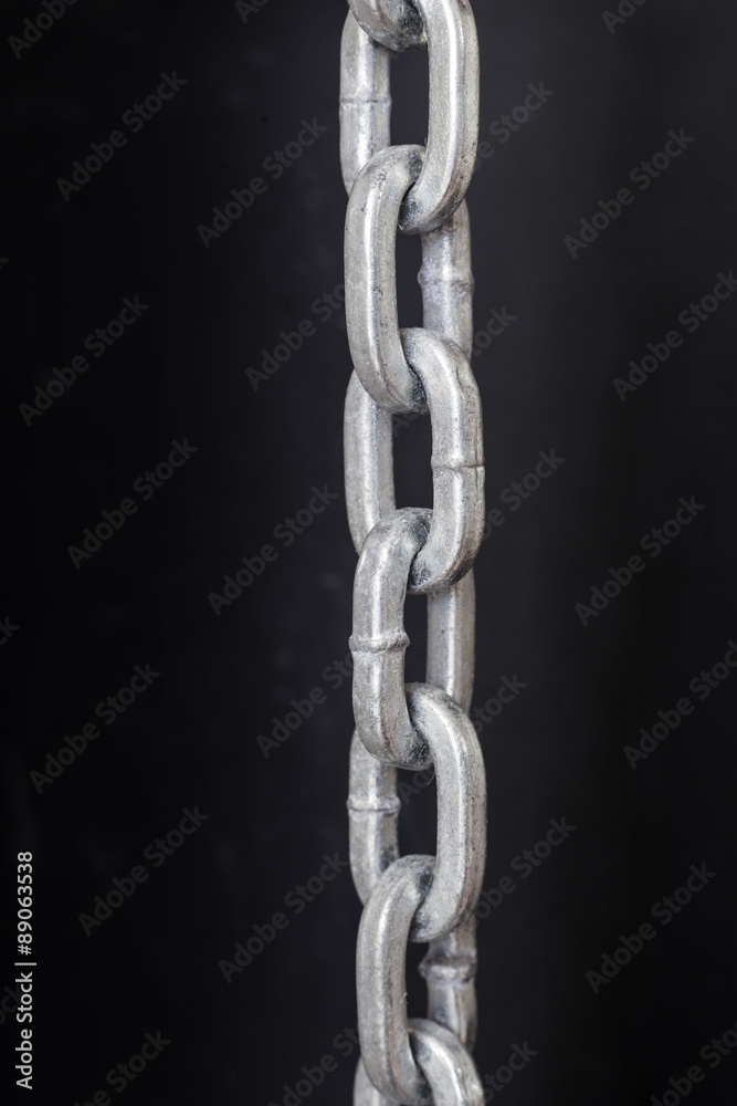part of metal chrome chain against dark background part of metal chrome chain against dark background