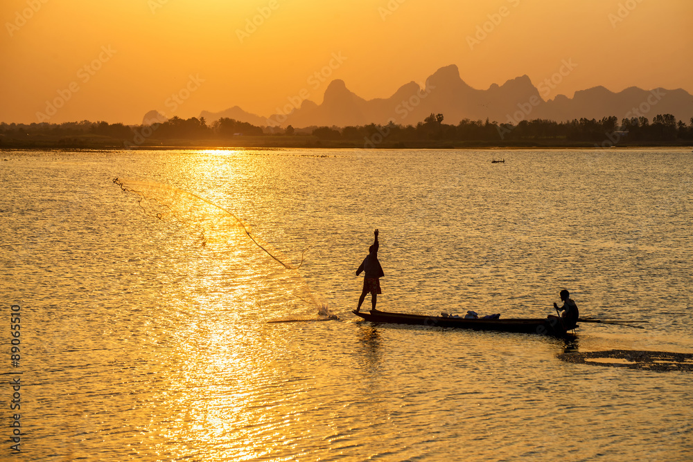 A silhouette fisherman throw a net to catch a fish in a river in