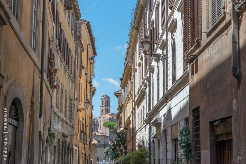 Straßenschlucht mit Ausblick auf Kirche vor blauem Himmel in Rom