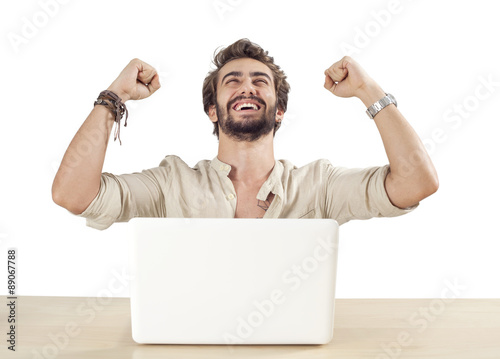 Young man with raised fists using laptop photo