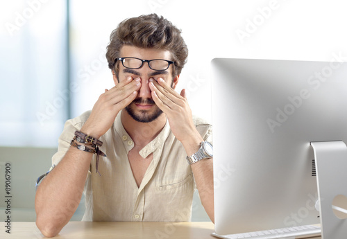 Young man with eyes pain touching his eyes