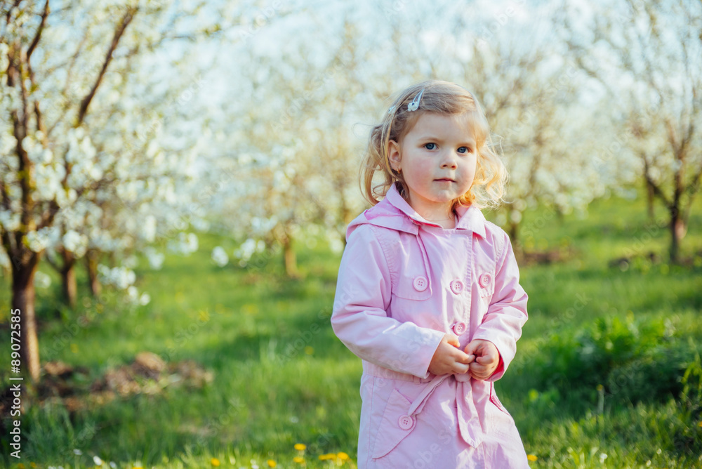 Little baby girl 3 years, that runs between flowering trees outd Little baby girl 3 years, that runs between flowering trees outd