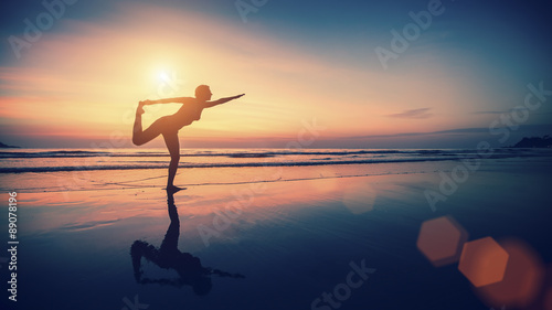 Silhouette exercises girl on the background of the sea and sunset. Fitness and healthy lifestyle.