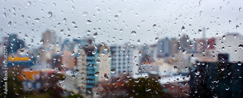 Obraz na plátně Panoramic urban view of rain drops falls on a window