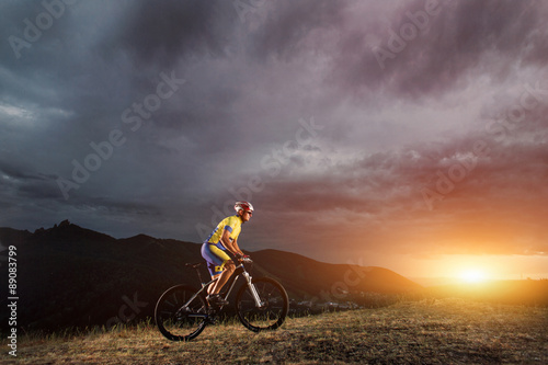 mountain bike cyclist riding track on grass rocky trail above su