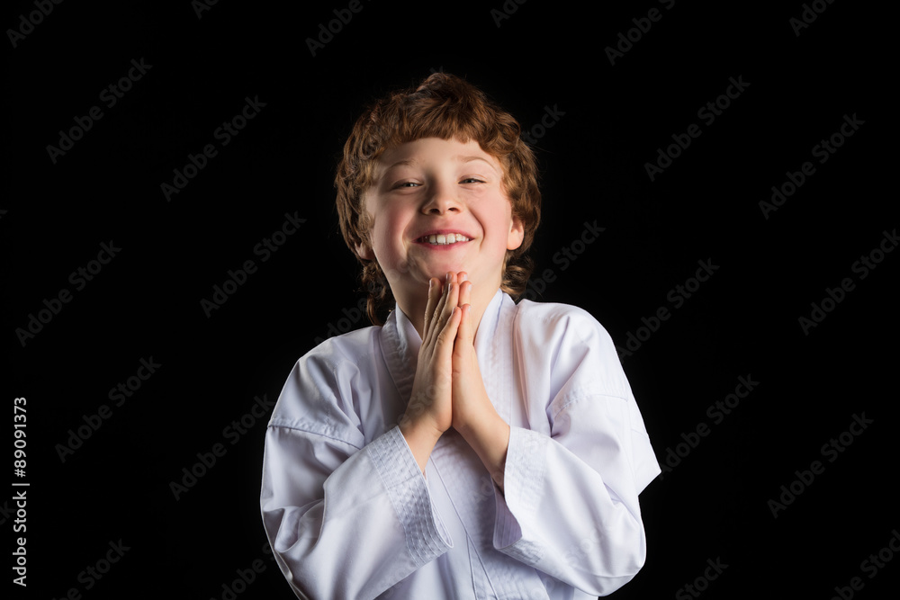 Smiling karate boy in white kimono isolated on black background Smiling karate boy in white kimono isolated on black background