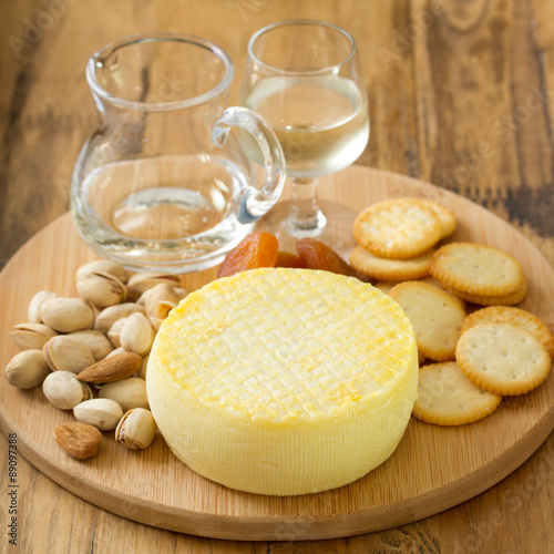 cheese with cookies, nuts and wine on tray on brown background
