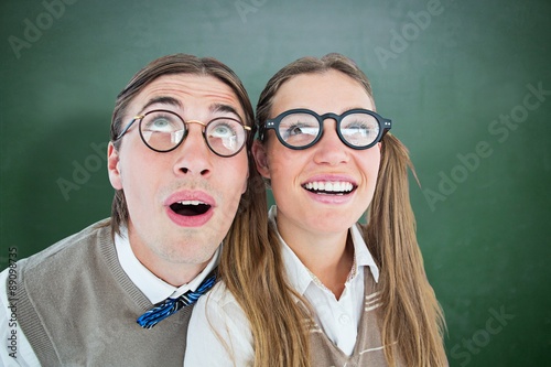 Composite image of geeky hipster couple raising eyes