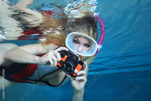 Sexy female snorkeler with neoprene swimsuit and underwater camera  photo