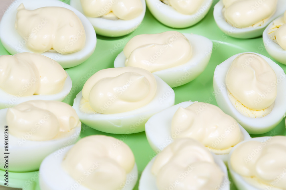slices of boiled chicken eggs with mayonnaise on a green plate slices of boiled chicken eggs with mayonnaise on a green plate