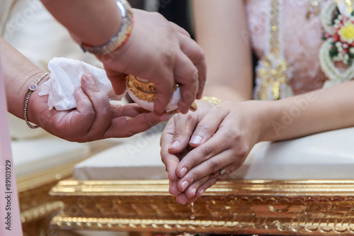 Close-up of water being poured on the hands of the bride during a traditional Thai wedding ceremony.