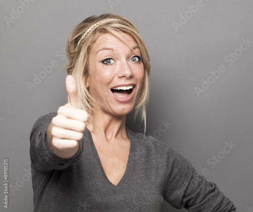 Bild auf Leinwand satisfaction concept - thrilled young woman with trendy blonde hair giving a thu