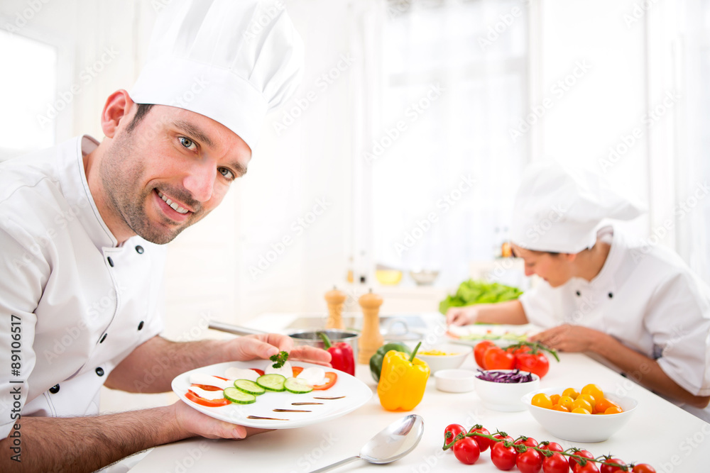 Young attractive professional chef cooking in his kitchen