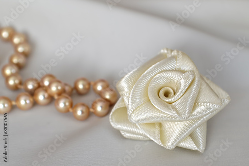 Handmade silk rose and pearls on white background