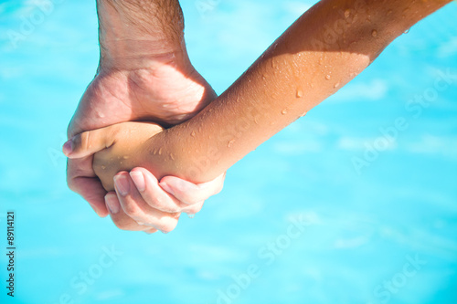 father holding the hand of his son in the swimming pool