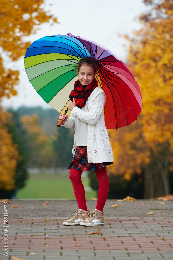 Obraz premium girl under rainbow umbrella in autumn park