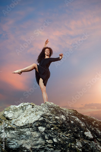pretty, young, curly dancer posing in the Rocky Mountains at sunset.