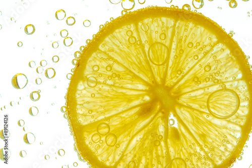 Fresh lemon slice in water with bubbles on white background