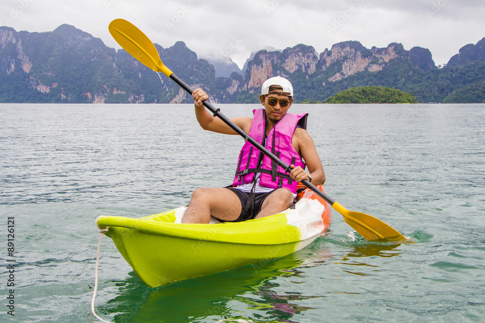 Young Asia man paddling in Chiewlarn dam in Surat Thani, Thailand