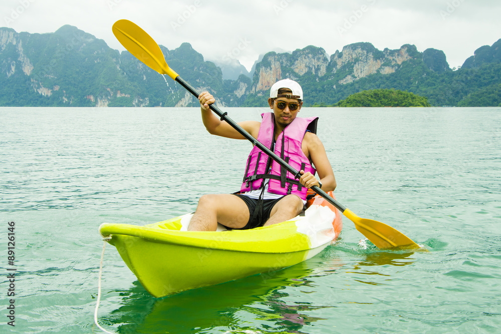 Young Asia man paddling in Chiewlarn dam in Surat Thani, Thailand