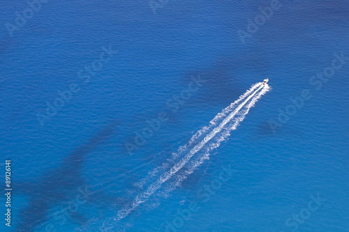 Aerial image of motorboat floating in a turquoise blue sea water. 