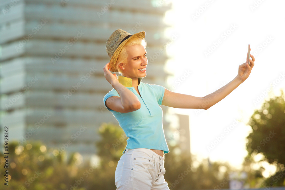 Smiling young woman taking selfie portrait outside