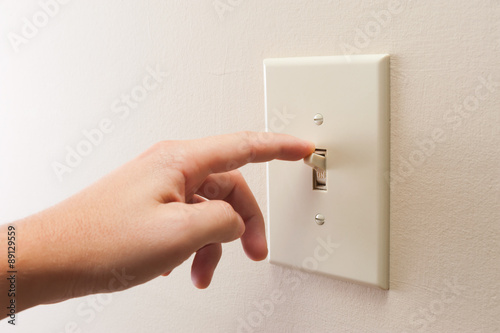 Hand turning wall light switch off. color image in horizontal orientation photo