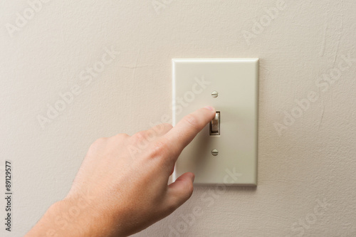 Hand turning wall light switch off. color image in horizontal orientation
