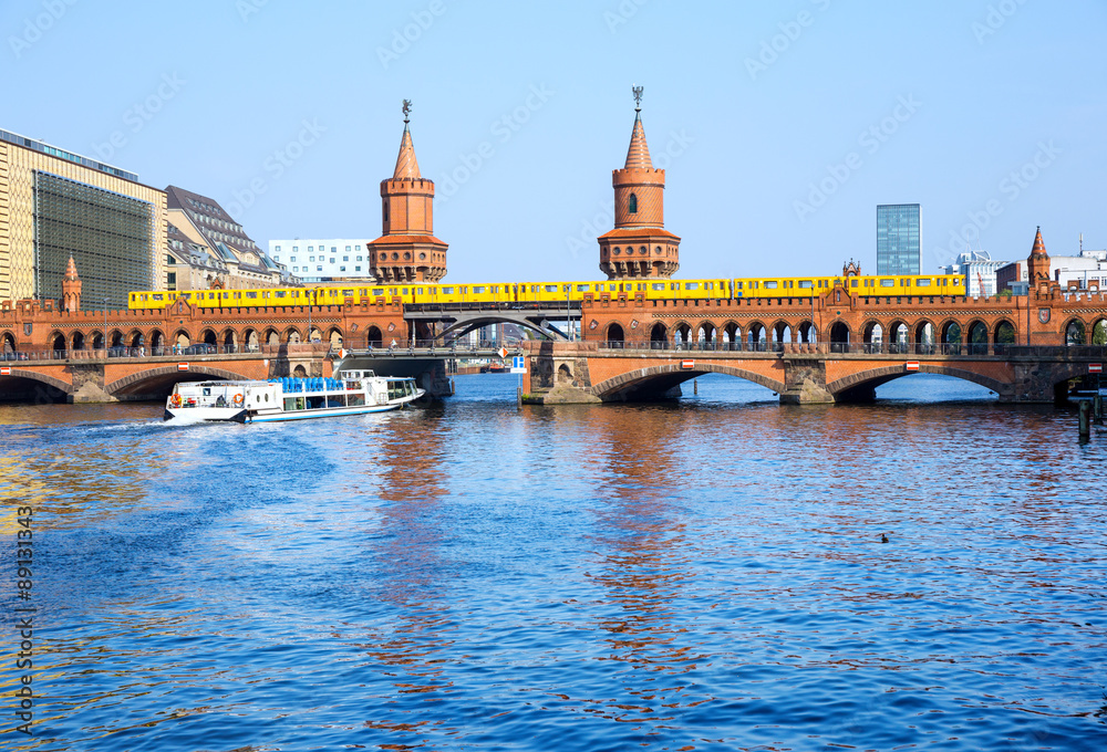 Fototapeta premium Oberbaumbrücke (Oberbaum Bridge) with subway and boat on the river Spree, Berlin