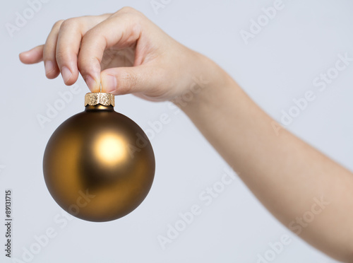 Gold color christmas ball holding by fingersThis shot was produced by Canon 5DS, 50-megapixel  photo