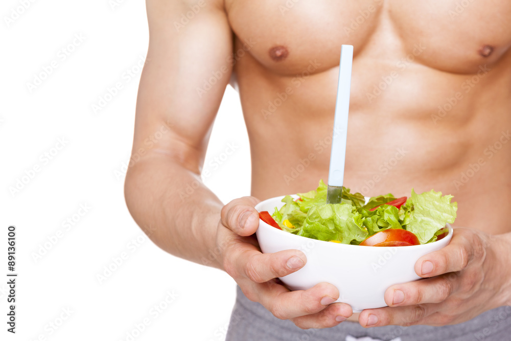 Close-up of a muscular man holding a bowl of salad, isolated on Close-up of a muscular man holding a bowl of salad, isolated on