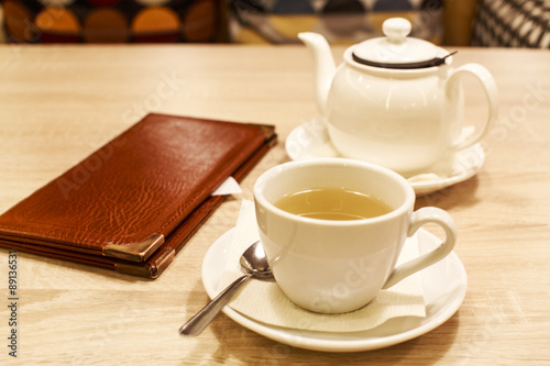 restaurant bill. folder with the score at restaurant table with a teapot and a cup of tea