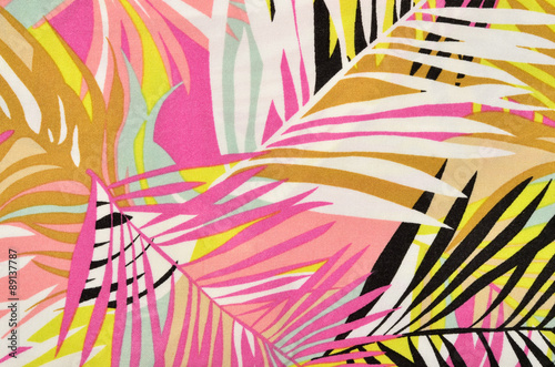 Colorful tropical leaves pattern on fabric. Pink, yellow, black and white palm leaves print as background.