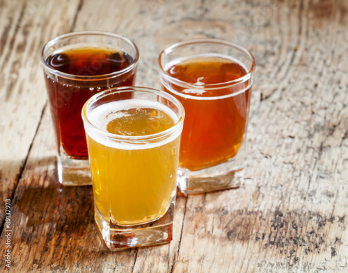 Three kinds of beer on old wooden background, selective focus