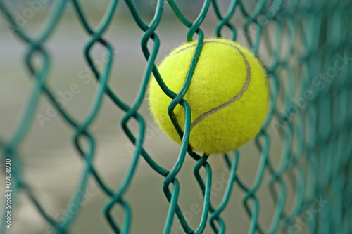 tennis ball in the chainlink behind court © leisuretime70